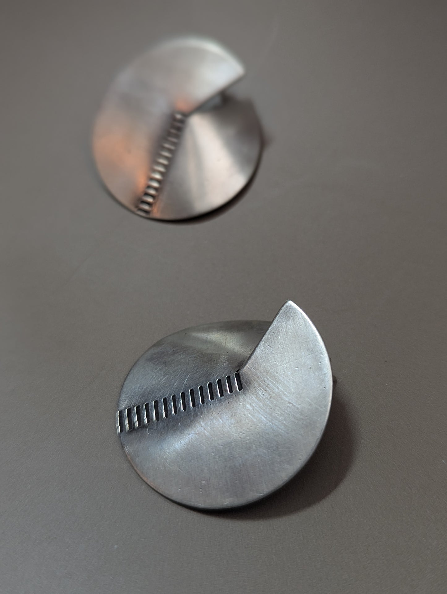 Close-up of brushed sterling silver earrings with notch and stamped lines, modern geometric handmade earrings. Boho chic, élégante and minimalist.
