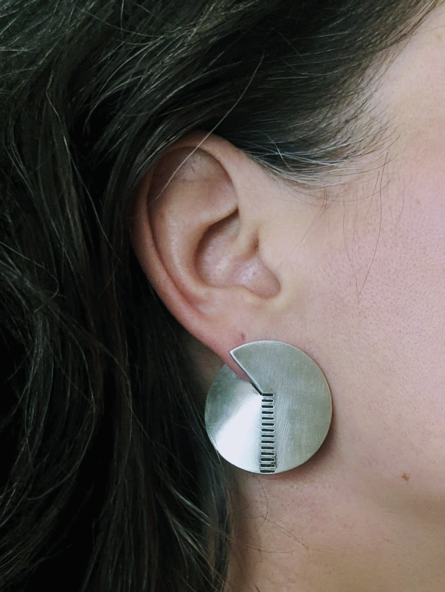Model wearing brushed silver sterling earrings with notch and line detail. Artisan minimalist silver jewelry.