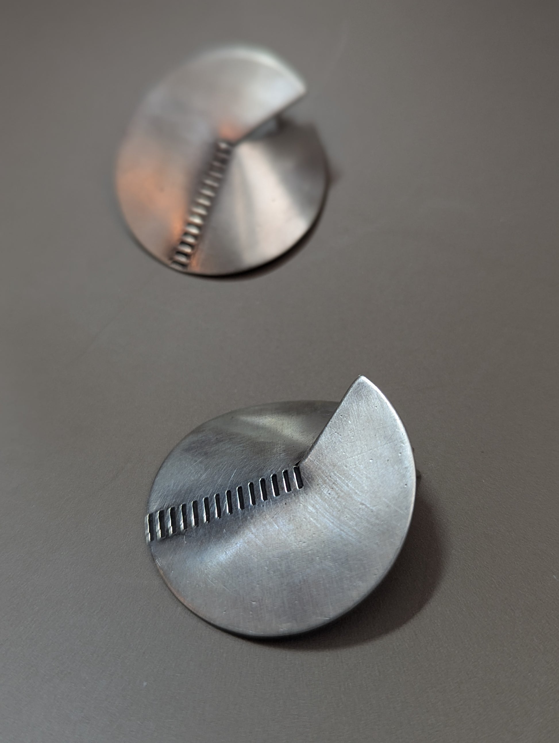 Close-up of brushed sterling silver earrings with notch and stamped lines, modern geometric handmade earrings. Boho chic, élégante and minimalist.